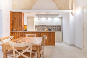 Eine Küche mit Holzausstattung, einem Esstisch mit Stühlen und einer gefliesten Spritzschutzwand.
