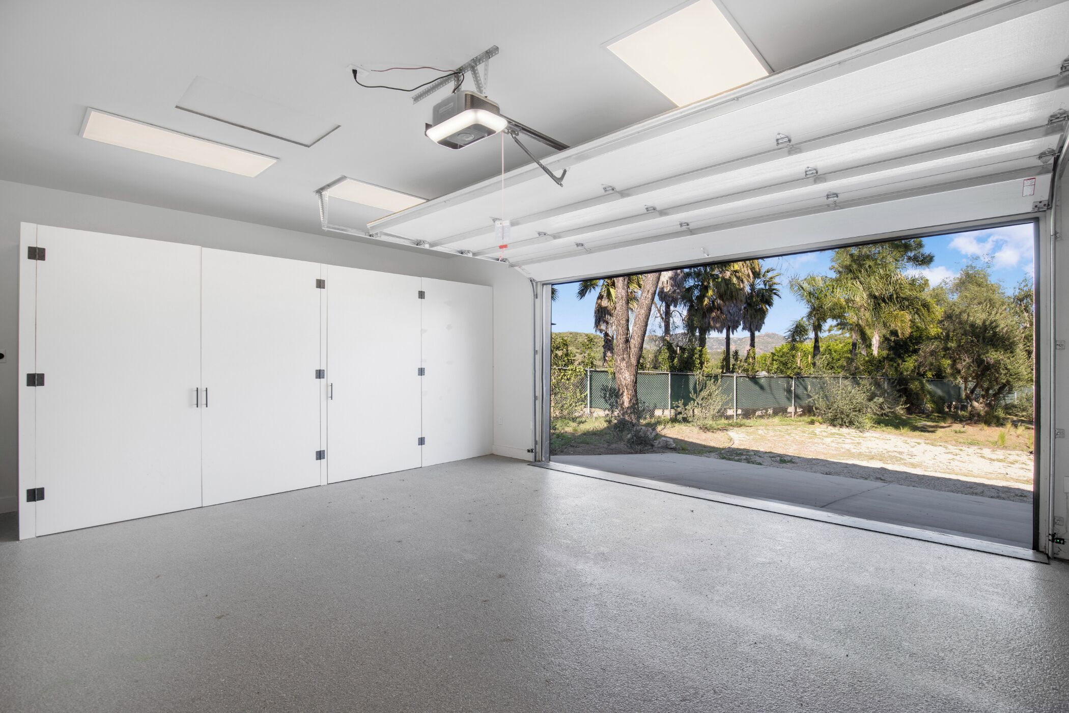A spacious room with a large sliding door leading to an outdoor area, ceiling-mounted lighting, and a projector.