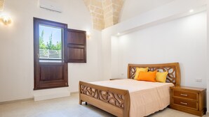 A bedroom with a bed, nightstand, and a window with a view. - Room 'Piano Terra' with Private Garden, Wi-Fi and Air Conditioning (Pulsano)
