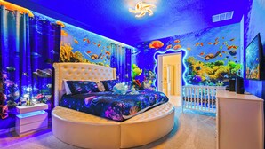 A round bed with a tufted headboard in a room with an aquarium wall and a ceiling light. - 3613LL Windsor Island (Davenport)