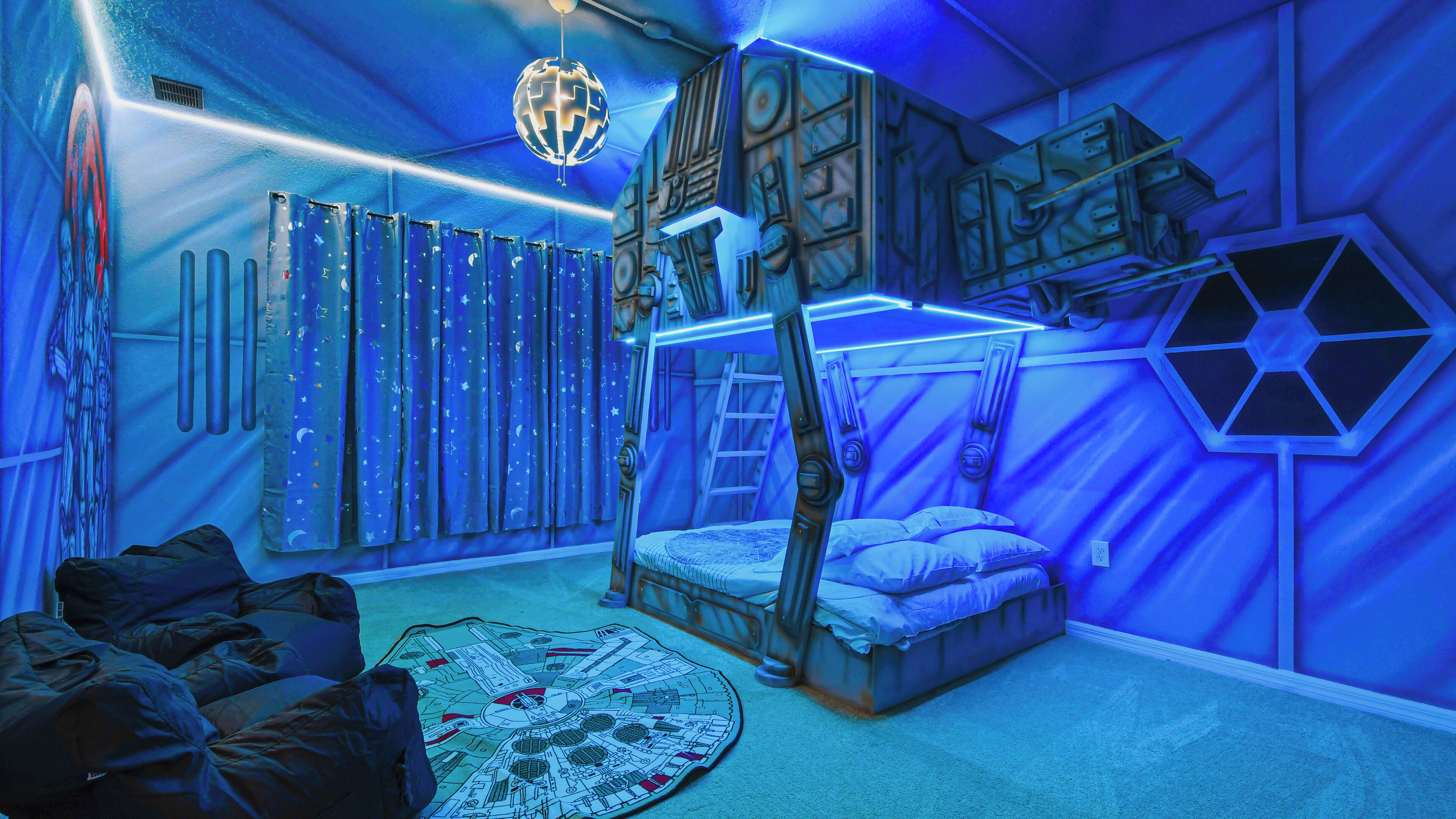 Una habitación con literas, una escalera, un globo colgando del techo y una cortina con motivos de noche estrellada.
