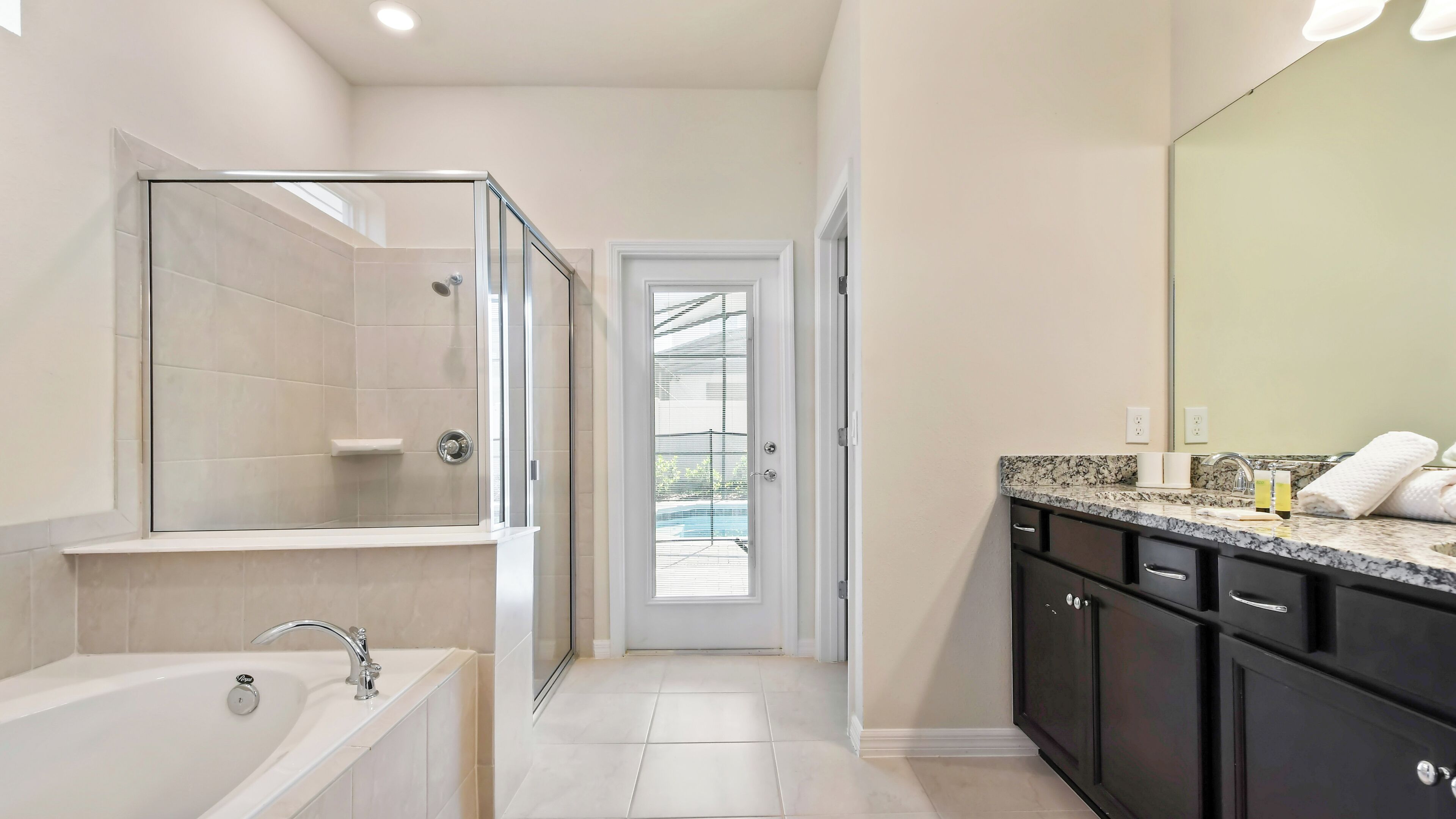 A modern bathroom with a glass-enclosed shower, a bathtub, a vanity with a sink, and a large mirror.