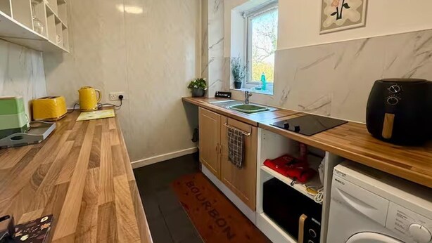 A compact kitchen with wooden countertops, a built-in oven, a sink, and a window.