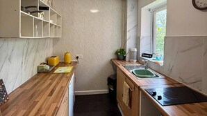 A compact kitchen with wooden countertops, a built-in oven, a sink, and a window with a view.