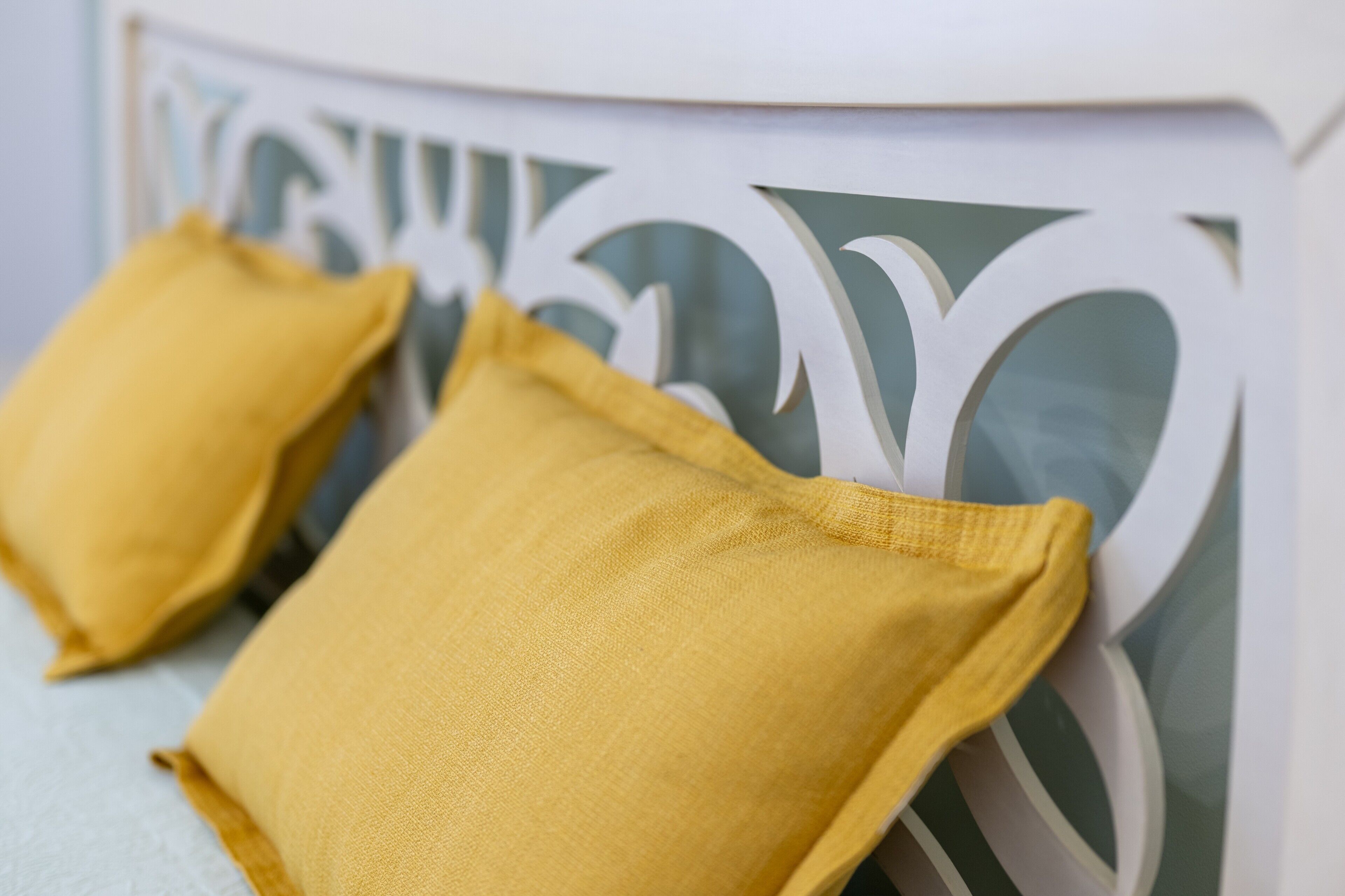 Une chaise blanche dotée d’un dossier décoratif et de deux coussins jaunes.