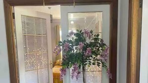 A hallway with wooden flooring, a potted plant with purple flowers, and a hanging sign with Arabic script. - Relaxing 5-star Farm Stay, Sleeps 20 With Spa! (Shotts)