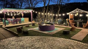 An outdoor patio area with a fire pit, seating, and string lights. - Relaxing 5-star Farm Stay, Sleeps 20 With Spa! (Shotts)