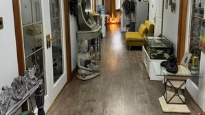 A hallway with a wooden floor, a yellow sofa, a glass table with a fish tank, and a statue. - Relaxing 5-star Farm Stay, Sleeps 20 With Spa! (Shotts)