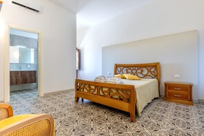 A bedroom with a bed, bedside table, and a bathroom visible through an open door.
