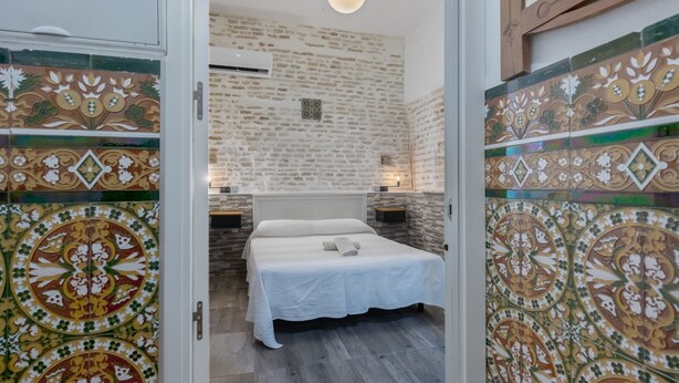 Un dormitorio con cama, lámpara colgante y pared decorada.