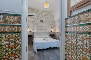 A bedroom with a bed, a hanging light fixture, and a wall with a decorative pattern.