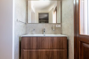 A bathroom with a wooden vanity, a mirror, and a sink. - Apartment 'Primo Piano - Mini' with Private Garden, Wi-Fi and Air Conditioning (Pulsano)