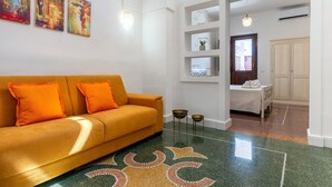 Una sala de estar moderna con un sofá, un tapiz estampado y un pasillo que conduce a un dormitorio.