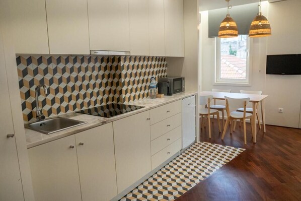 Une cuisine moderne avec un revêtement mural géométrique, un évier encastré et un coin repas comprenant une table et des chaises.
