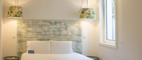 A modern bedroom with a large bed, wooden flooring, a textured wall, and two pendant lights.