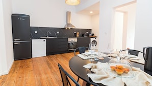 Una cocina moderna con armarios negros, piso de madera y un comedor con una mesa redonda dispuesta para cuatro personas.