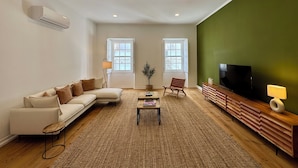Una sala de estar con un sofá, una mesa de centro, un televisor y una pared verde decorativa.