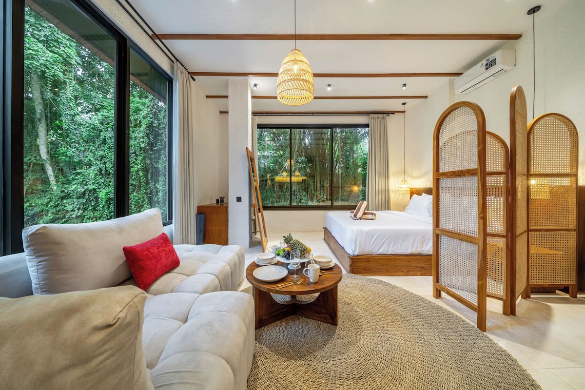 Une chambre moderne avec une grande fenêtre, un lit, un canapé et une table à manger.