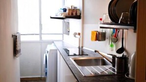 A compact kitchen with a sink, a washing machine, and a window providing natural light.