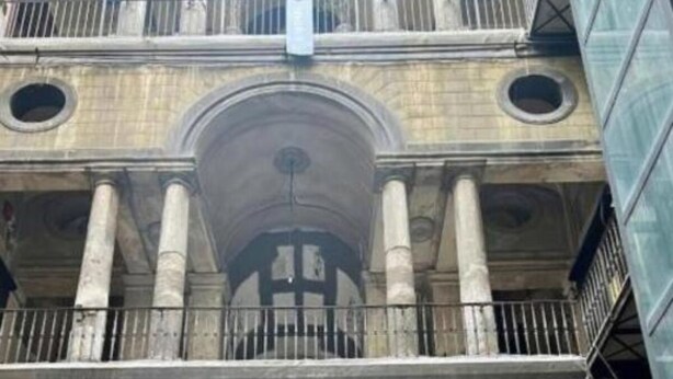 A multi-story building with a central arched entrance, columns, and balconies.