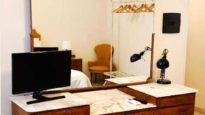 A wooden dresser with a mirror, a television on top, and a lamp beside it.