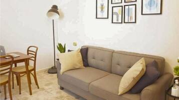 Ein Wohnzimmer mit einer Couch, einem Couchtisch und einer Lampe. An der Wand hängen gerahmte Bilder.