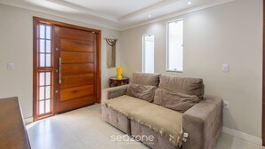 A living room with a beige sofa, a wooden door, and a small table with a yellow lamp. - House With Pool and Barbecue Ekd0397 (Picarras)