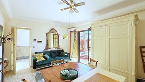A spacious living room with a wooden dining table, a sofa, and a ceiling fan. - Solemar Sicilia - Palazzo Tiglio (Porticello)