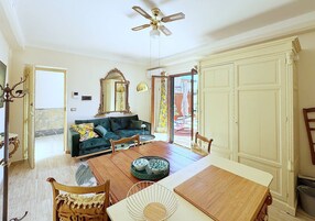 Amplia sala de estar con una mesa de comedor de madera, un sofá y un ventilador de techo.