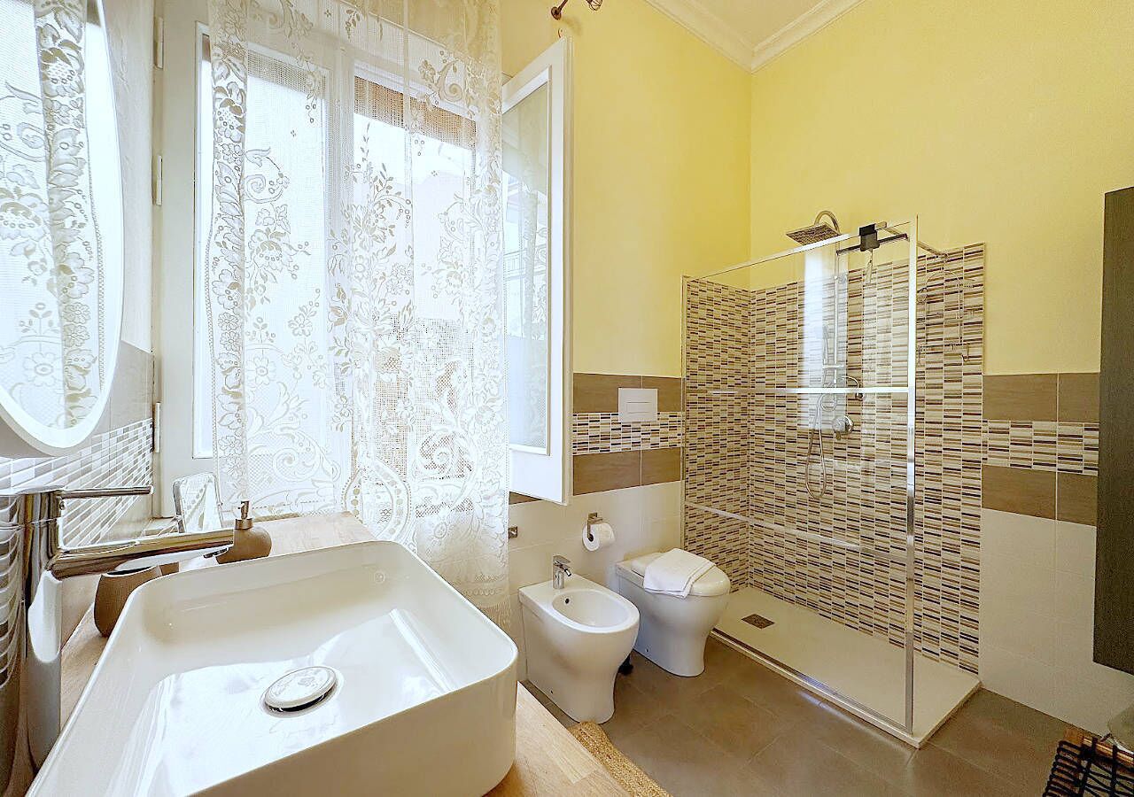 A bathroom with a large sink, toilet, bidet, and shower area.
