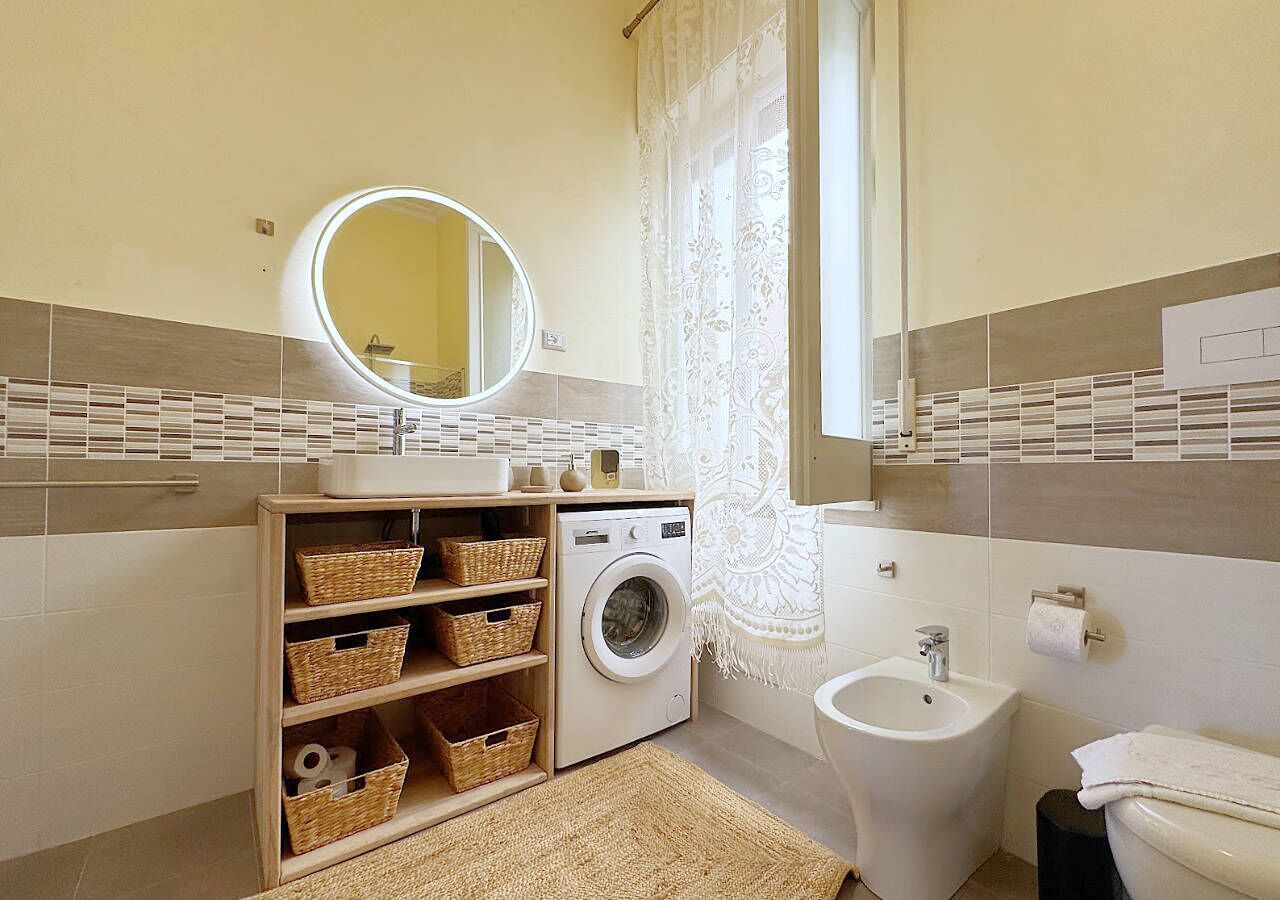 Un baño con lavadora, lavamanos, bidé y espejo.