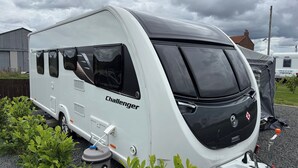 A white caravan with the brand name 'Challenger' on its side, featuring a large front window, a compact kitchen area, and a small storage compartment. - 4 Guests - Pet Friendly - Durham Caravan Retreat (Durham)