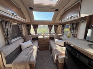 Ein gemütliches Wohnmobil-Interieur mit einer zentralen Sitzecke, einer Küchenzeile und einem Esstisch.