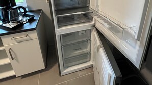 Et køkken med indbygget køleskab, kaffemaskine og et vindue.