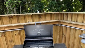En grill med sort ydre og et træhegn i baggrunden.