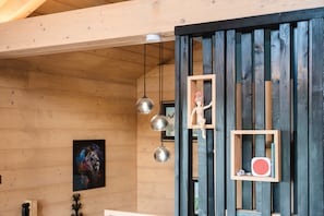 Un intérieur en bois, avec une étagère à ossature en bois sur laquelle sont posés une petite figurine et un objet rouge.