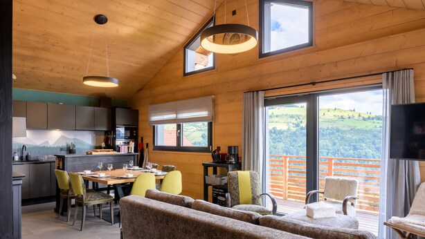 A cozy interior with a dining area, kitchen, and a balcony with a scenic view.