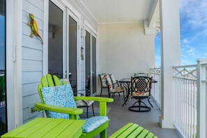Een balkon met groene stoelen en een tafel, een decoratieve hagedis, en uitzicht op de lucht.