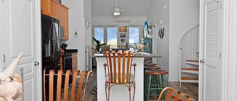 Ett modernt kök med träskåp, ett kylskåp och en matplats med ett glasbord och stolar.