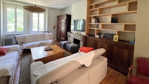 A living room with a fireplace, a television, and a bookshelf. - Family home in green setting near village, municipal swimming pool, nogaro (Panjas)
