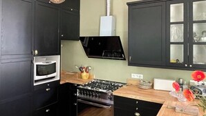 A kitchen with dark cabinets, a microwave, a stove, and a sink. - Family home in green setting near village, municipal swimming pool, nogaro (Panjas)