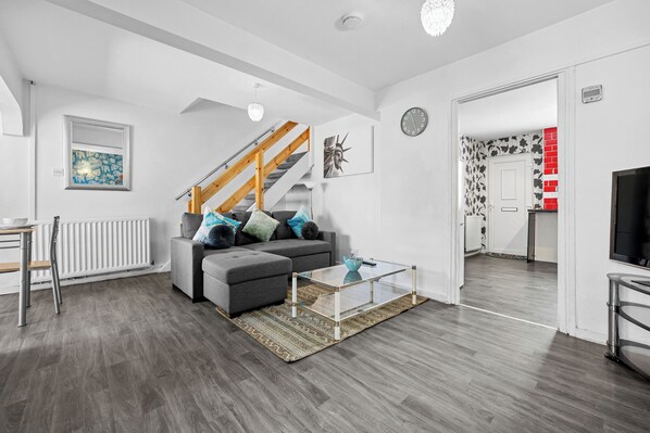 A modern living room with a sofa, coffee table, and staircase.