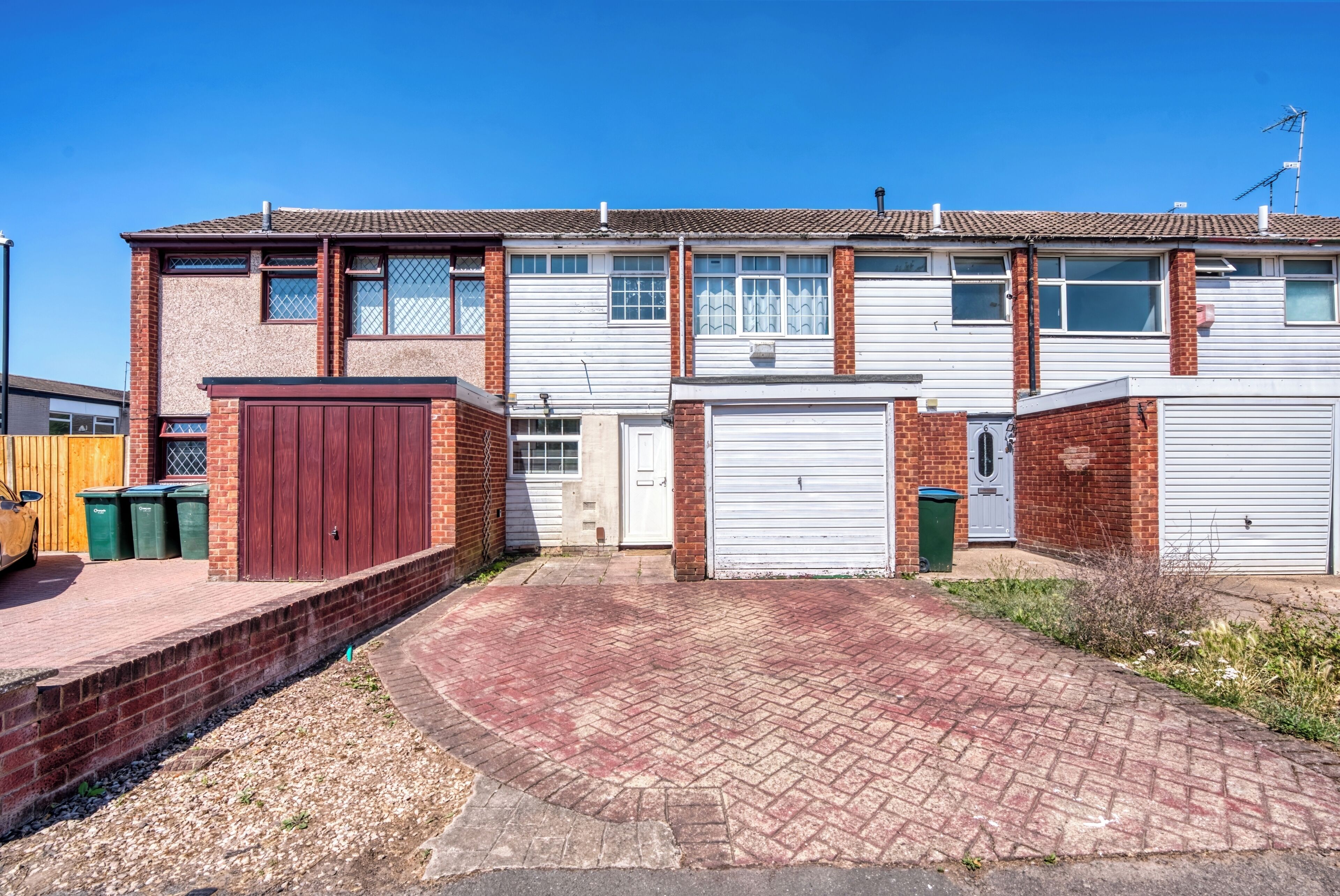 Un immeuble résidentiel de deux étages, doté d’un garage, d’une allée et d’un petit jardin.