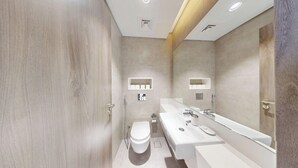 Ein modernes Badezimmer mit einem großen Spiegel, einer weißen Toilette und einem Doppelwaschbecken.