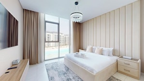 Ein modernes Hotelzimmer mit einem großen Bett, einem Nachttisch, einem Fernseher und Blick auf einen Pool und Gebäude.