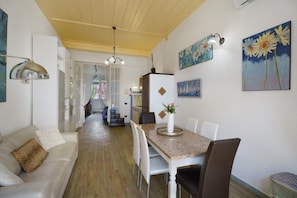 A dining area with a table, chairs, a vase with flowers, and a painting on the wall.