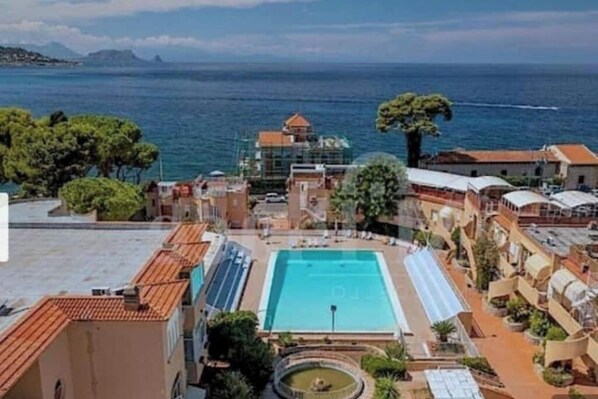 Un hotel con piscina, vistas al mar y una fuente circular.