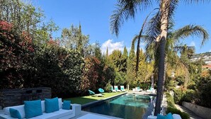 A poolside area with white outdoor furniture, a swimming pool, and surrounding greenery. - Villa Hamo - 6 rooms (Cannes)