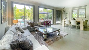 A spacious living room with a large sofa, a coffee table, and a dining area with a table and chairs. - Villa Hamo - 6 rooms (Cannes)