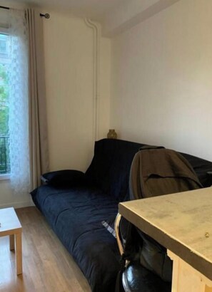 Una habitación con una cama, una mesita y una ventana con cortinas.